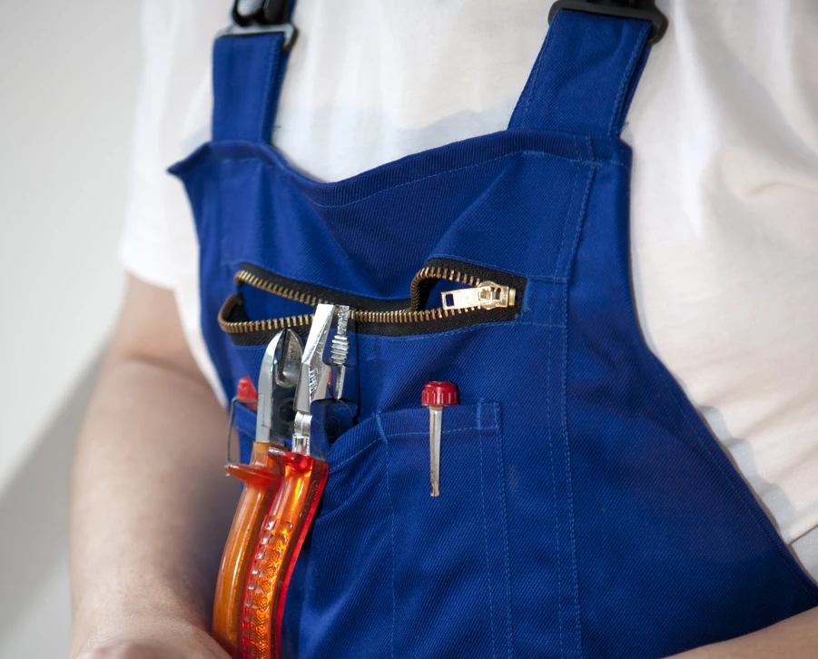 Artisan en salopette bleue portant des outils de bricolage et réparation
