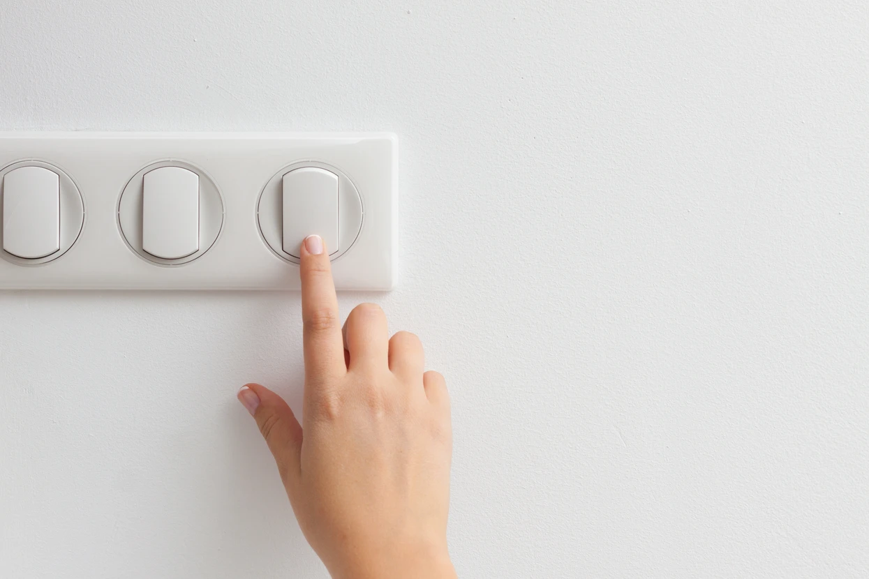 Doigt appuyant sur un interrupteur mural moderne dans un intérieur résidentiel contemporain