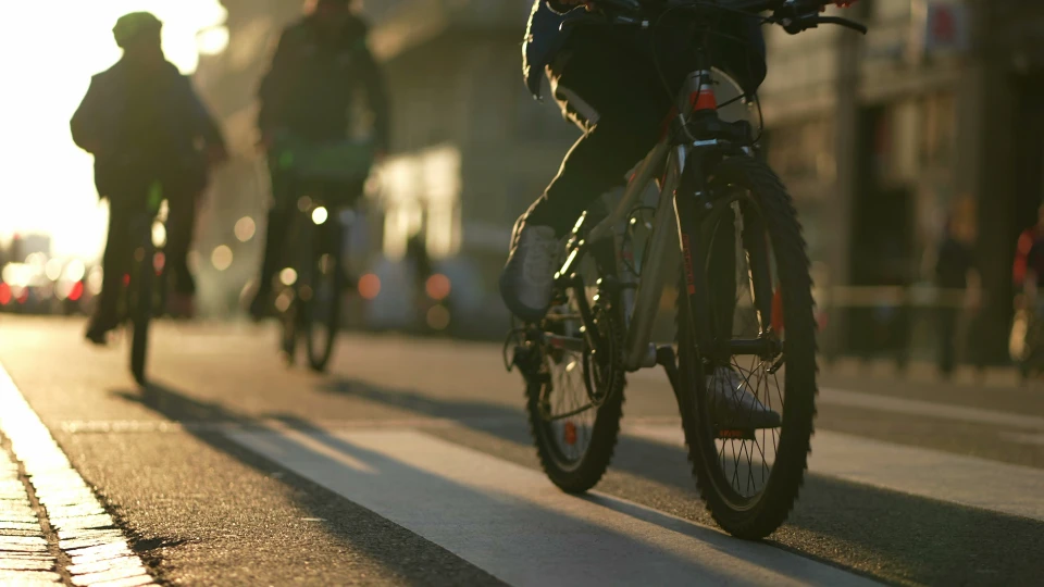 Femme en tenue décontractée manipulant un vélo pliant noir sur une place urbaine ensoleillée